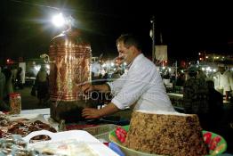 Image du Maroc Professionnelle de  Vendeur de Khoudenjale, une infusion tonifiante constituée de plusieurs herbes aromatiques : elle réchauffe et ouvre l’appétit, aphrodisiaque se prend avant ou après repas. sur la place Jamaa El Fana plusieurs vendeurs de cette tisane sont installés sur la place, ils la proposent avec une sorte de farine cuite mélangées aux amandes, graines de sésames, cacao… Une atmosphère un peu magique dans ces lieus au centre de Marrakech, le 1er Mars 2004. (Photo / Abdeljalil Bounhar)

 